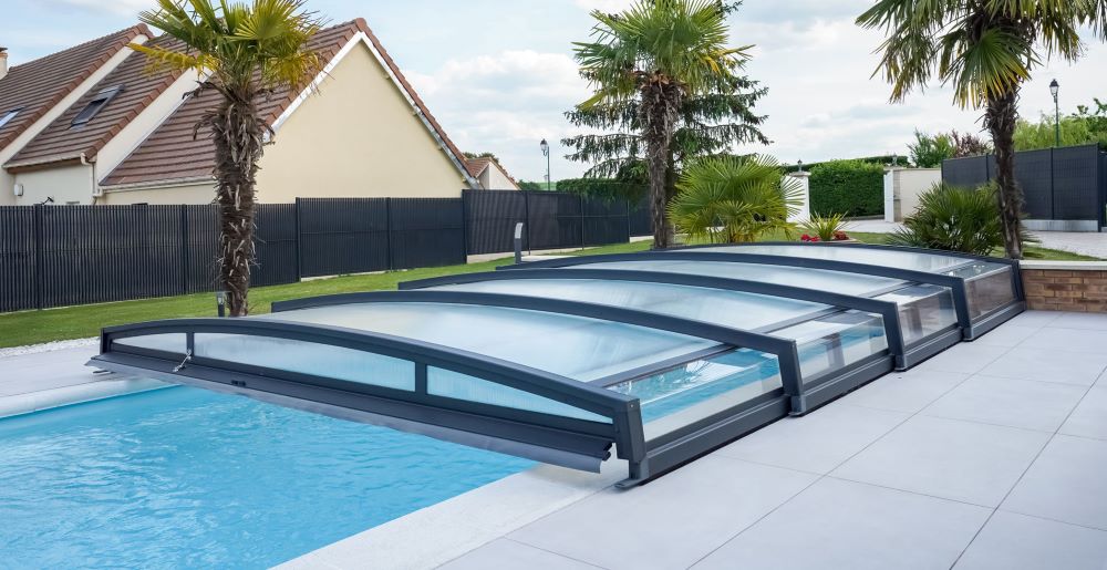 Abri de piscine bas coulissant en aluminium ouvert sur les côtés dans un jardin