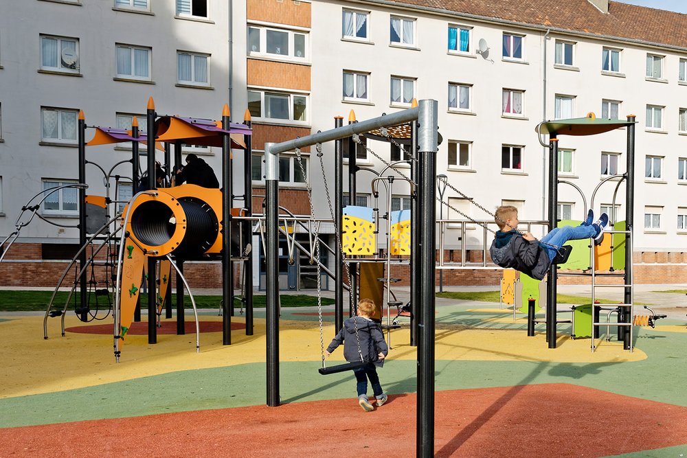 Aire de jeux pour enfants installée dans le jardin d'une copropriété avec toboggan et sol amortissant