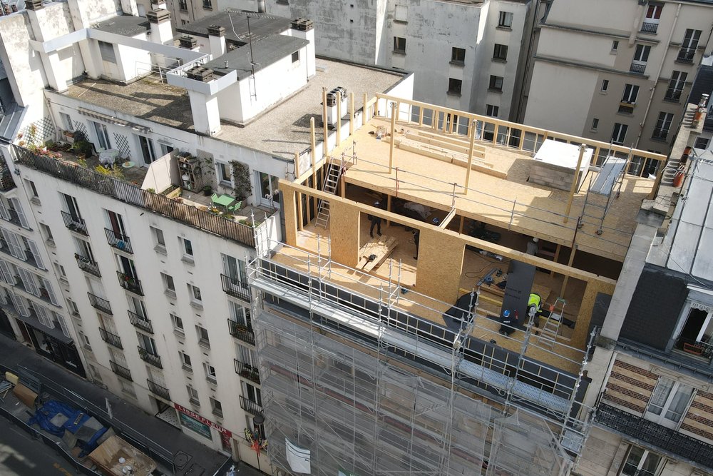 Chantier de surélévation en milieu urbain avec échafaudages sur toiture pour créer de nouveaux logements