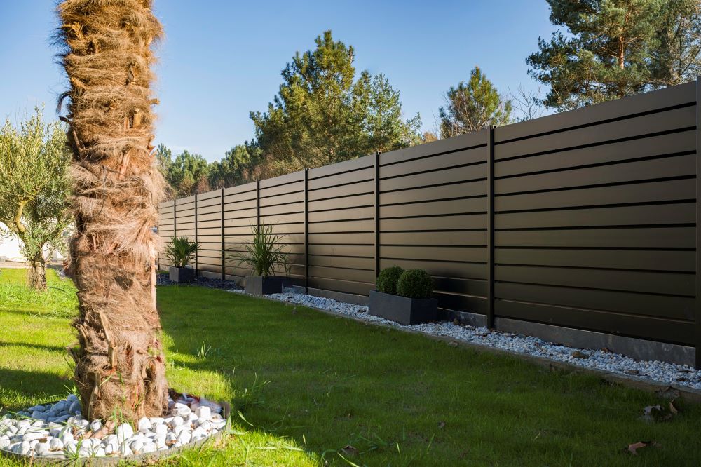 Clôture en limite de propriété entre deux jardins de maisons individuelles avec mur et grillage