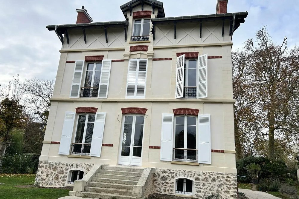 Façade d'une maison rénovée en zone protégée avec enduits minéraux et menuiseries peintes