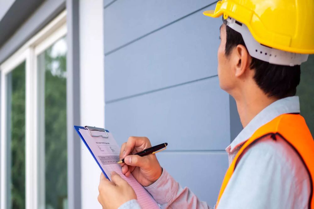 Agent du service urbanisme vérifiant la conformité d'une construction avec les plans du permis lors d'une visite de contrôle