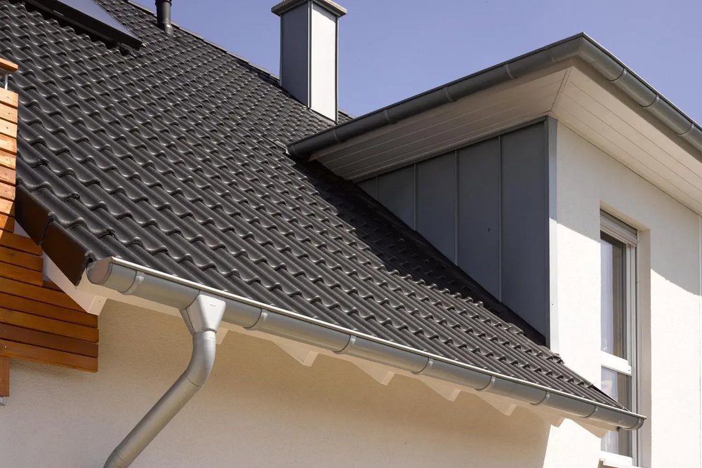 Détail technique d'une lucarne avec jouées en zinc prépatiné parfaitement intégrée à une toiture en ardoise
