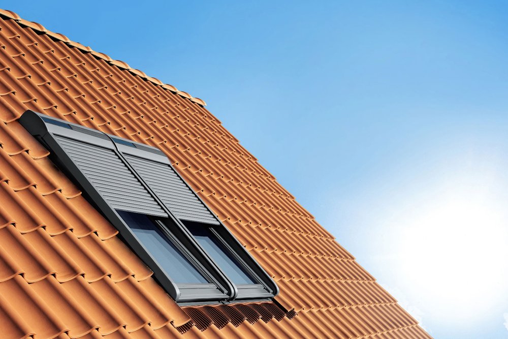 Fenêtre de toit installée dans des combles aménagés avec une protection solaire pour éviter la surchauffe