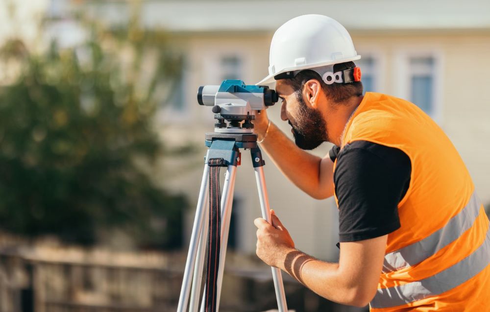 Géomètre-expert réalisant un levé topographique avec station totale sur un terrain en pente pour un projet de construction