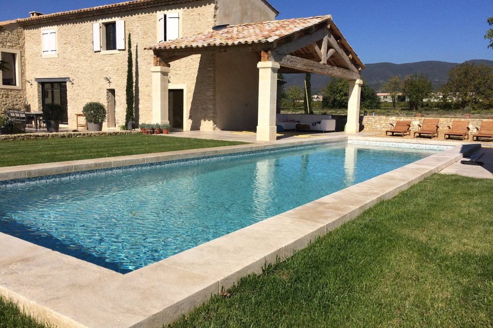 Piscine parfaitement intégrée dans son environnement paysager avec liner sombre et margelles en pierre naturelle