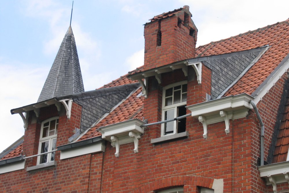 Lucarne rampante contemporaine intégrée sur une toiture en ardoise avec jouées en zinc