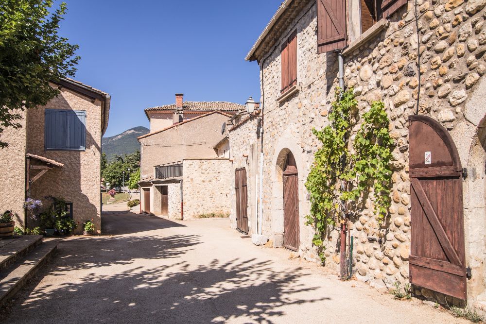Maison ancienne en pierre de pays avec extension en ossature bois illustrant les contraintes du bâti traditionnel