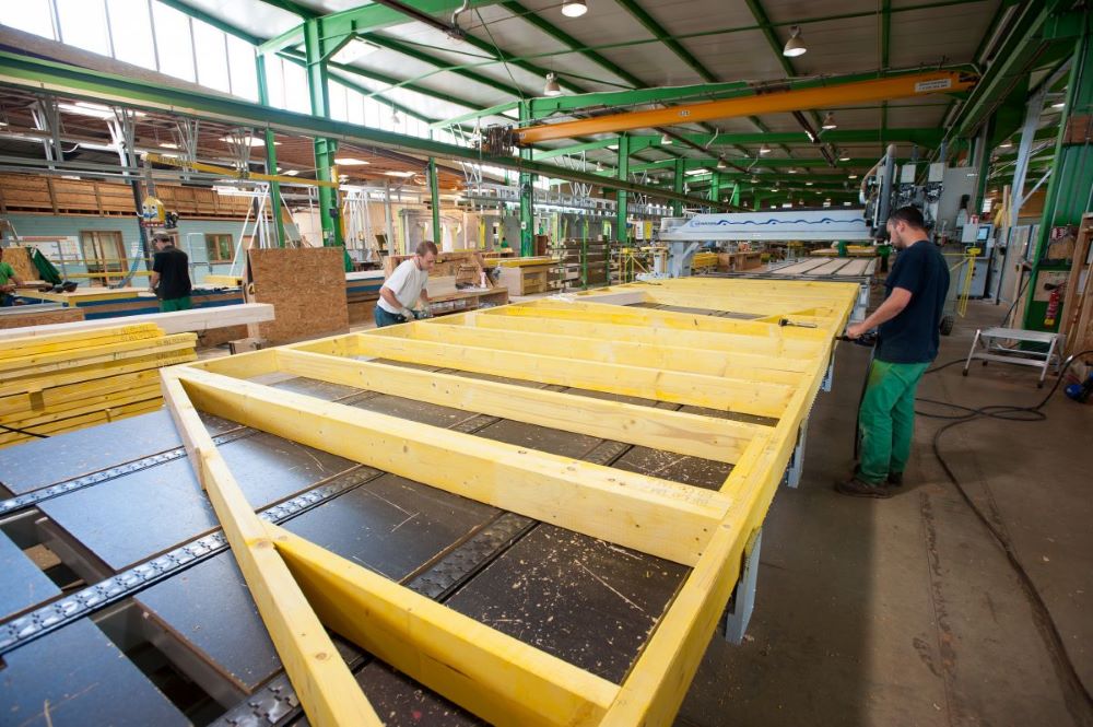 Fabrication en usine de panneaux d'ossature bois préfabriqués avec isolation intégrée pour une maison hors site