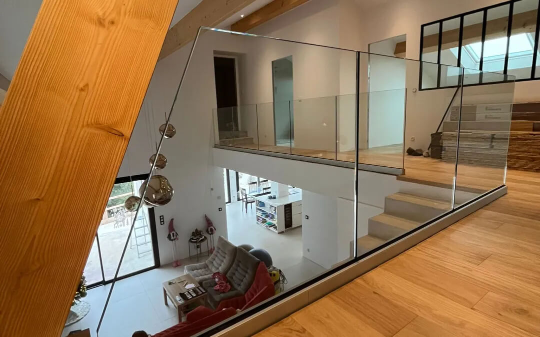 Mezzanine aménagée en chambre avec garde-corps en verre et escalier design dans un appartement