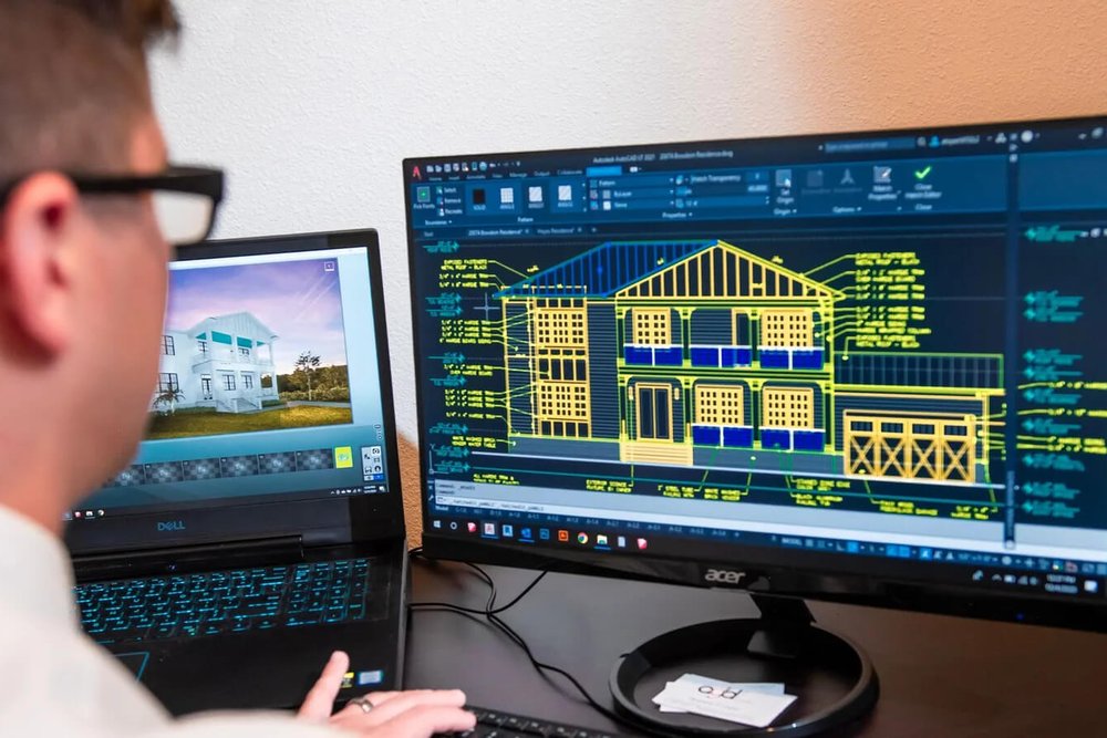 Dessinateur modifiant des plans de façade sur un logiciel de CAO pour intégrer des prescriptions d'urbanisme
