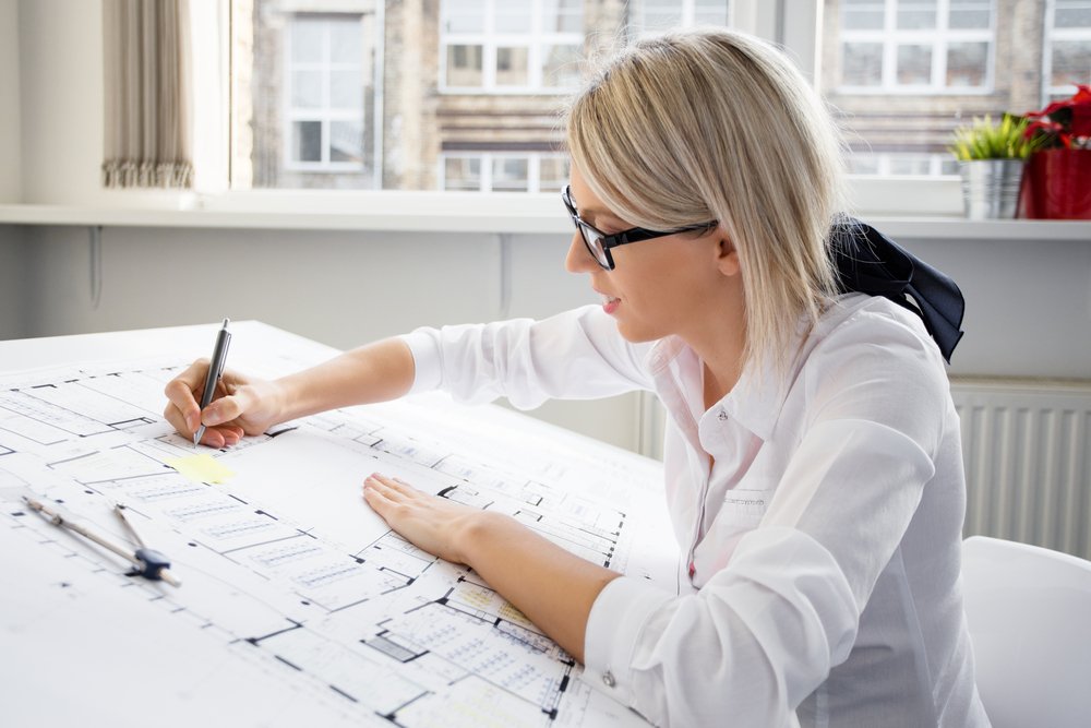 Dessinateur en bâtiment travaillant sur des plans modificatifs de construction sur un bureau avec outils de dessin