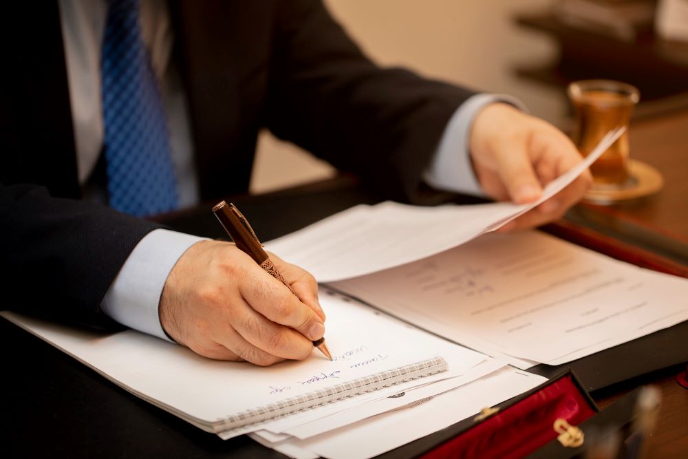Notaire et vendeur examinant l'acte de vente d'une maison avec clause sur des travaux non déclarés