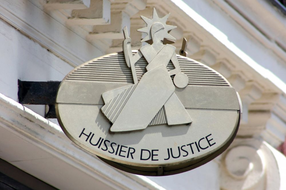 Constat d'huissier de justice réalisé devant un panneau de permis de construire pour prouver la date de début d'affichage