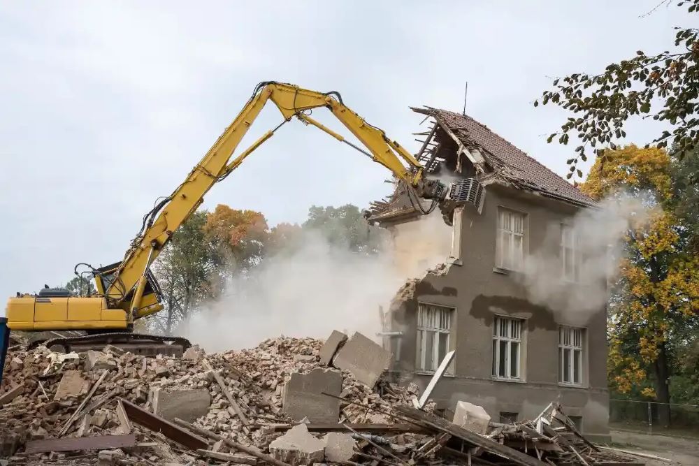 Démolition d'une maison ancienne avec engin de chantier pelle mécanique dans un quartier résidentiel