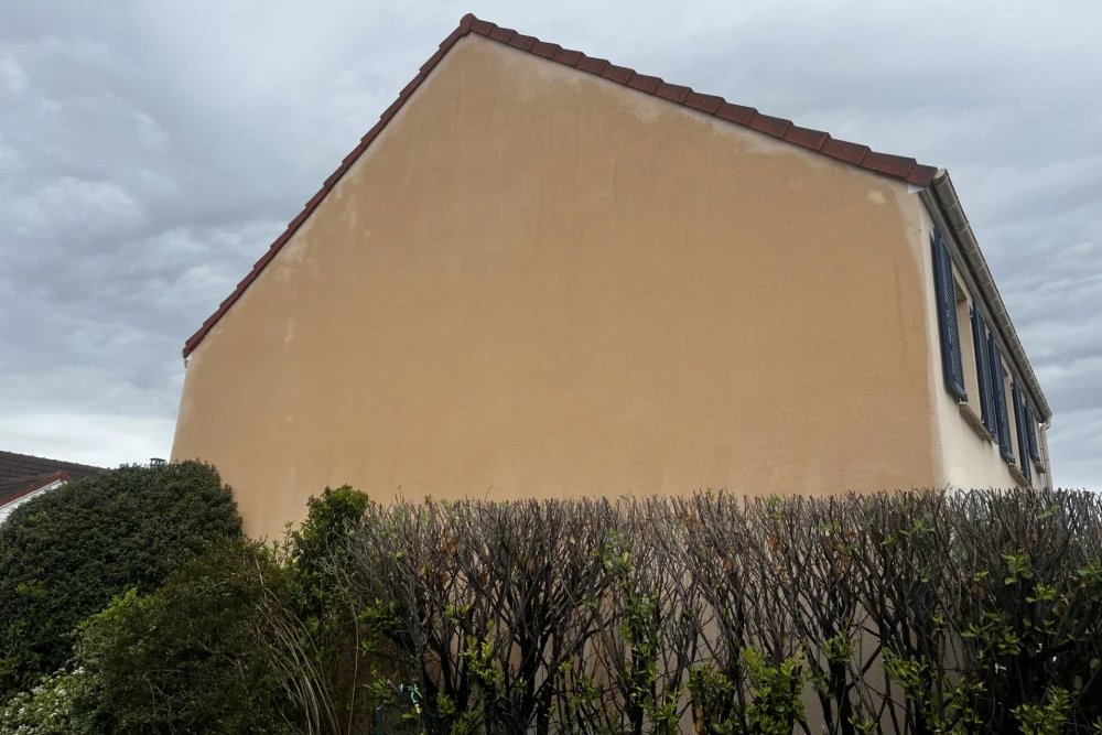 Pignon aveugle de maison individuelle en limite de propriété projetant une ombre portée sur la cour voisine