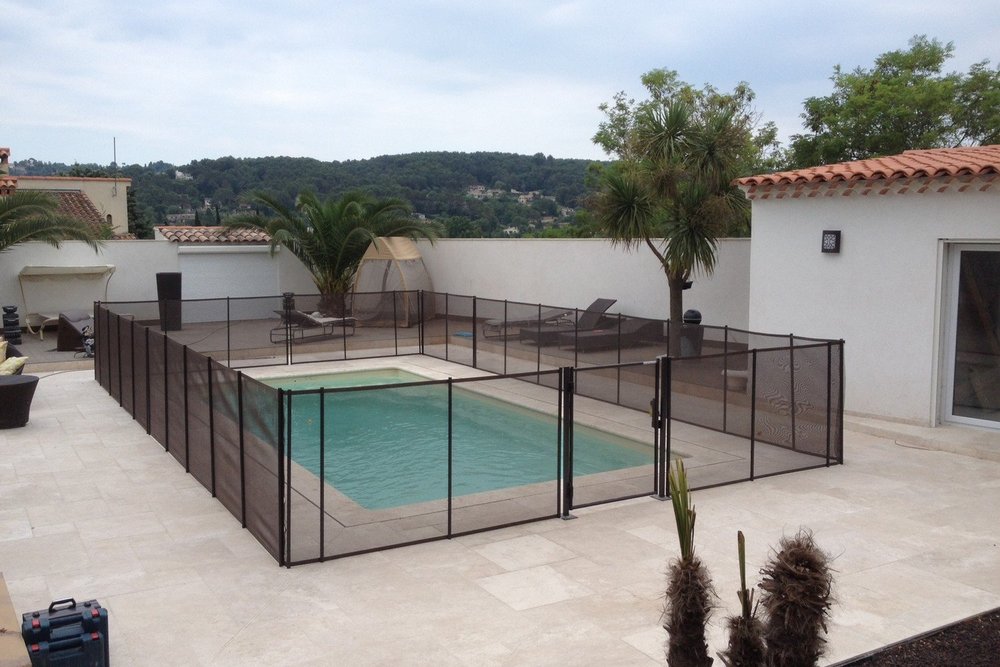 Jardin avec piscine entièrement sécurisée par un garde-corps continu autour du bassin en présence de jeunes enfants