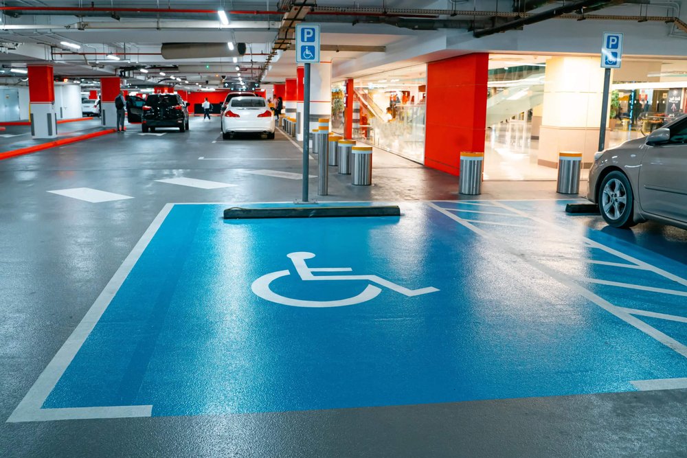 Place de stationnement PMR positionnée à proximité immédiate de l'entrée accessible d'un bâtiment commercial