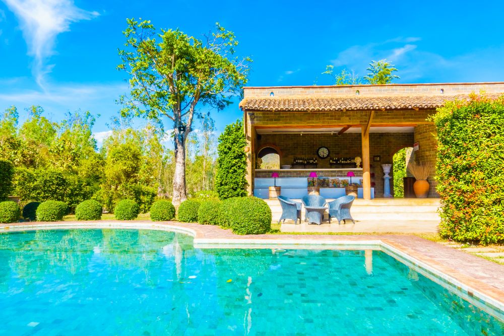 Pool house avec cuisine d'été, sanitaires et terrasse couverte au bord d'une piscine privée
