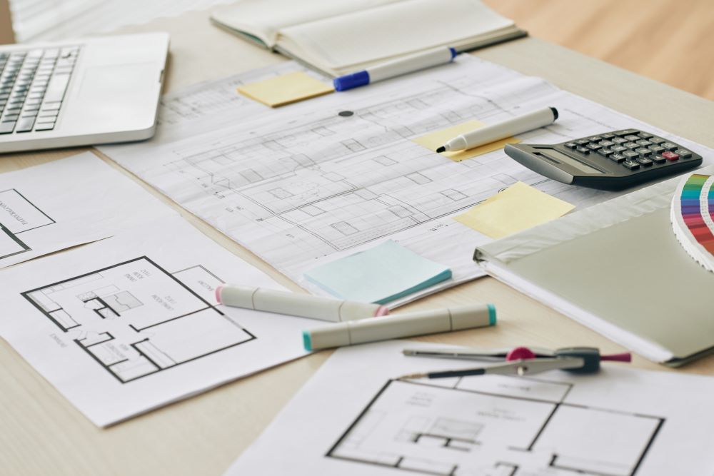 Dossier de régularisation de travaux non déclarés posé sur bureau avec plans de maison avant vente immobilière
