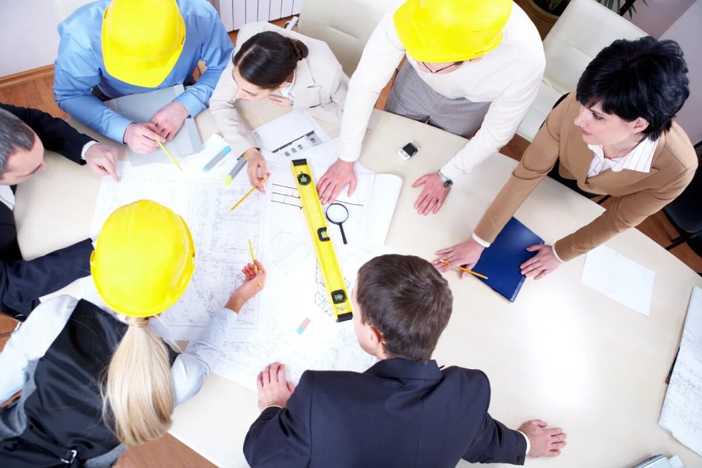 Réunion sur un chantier de construction d'une maison individuelle pour étudier des modifications de plans avec un professionnel