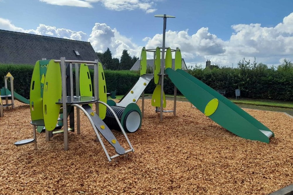 Sol amortissant en copeaux de bois installé sous un équipement de jeux pour enfants en copropriété