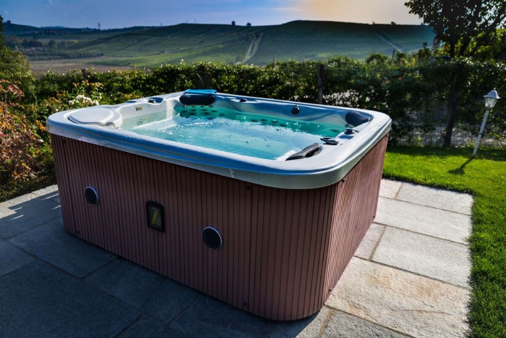 Spa jacuzzi hors-sol avec habillage bois installé dans le jardin d'une maison individuelle