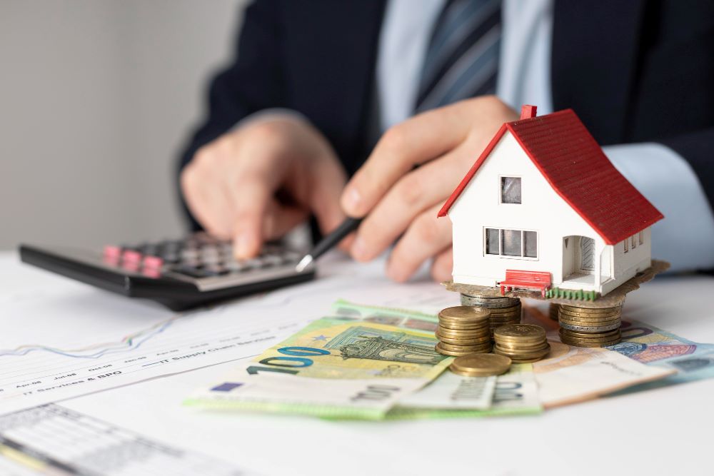 Avis de taxe foncière sur les propriétés bâties posé sur une table avec calculatrice et maison en arrière-plan