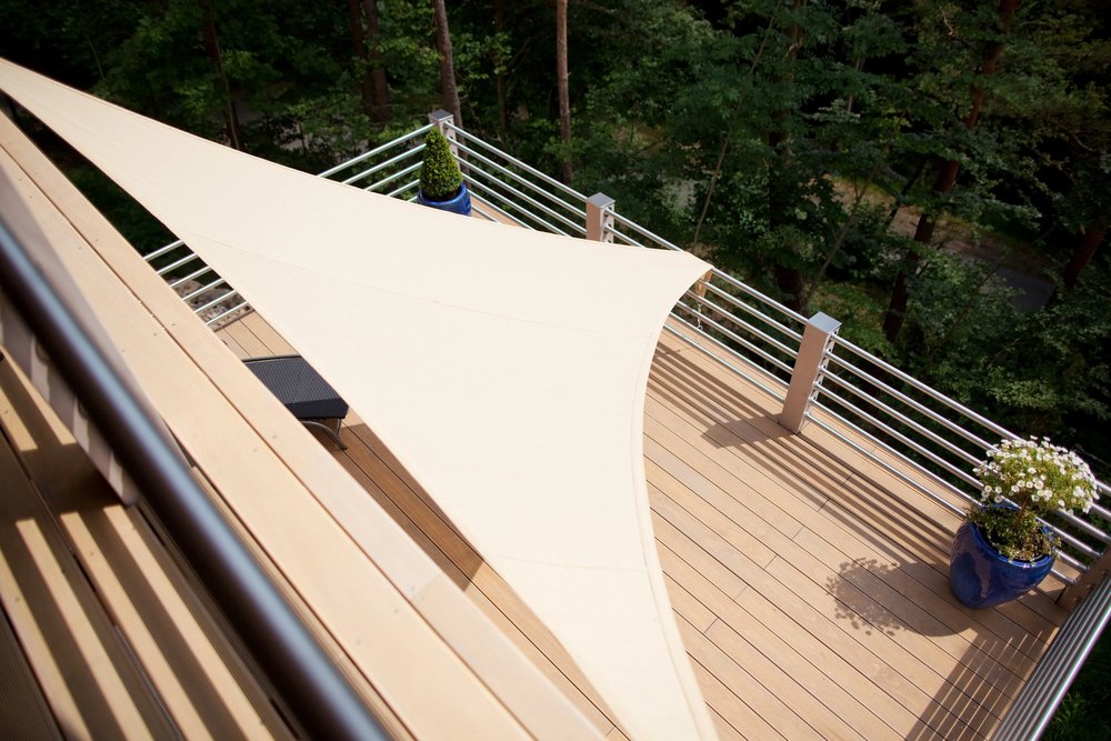 Terrasse sur pilotis en bois édifiée sur un terrain en pente avec garde-corps conforme aux règles de mitoyenneté