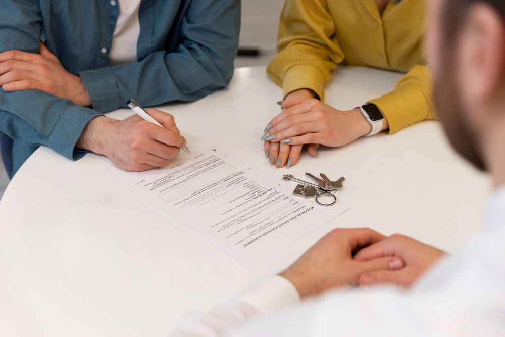 Dossier de demande de transfert de permis de construire posé sur un bureau avec acte de vente d'un terrain