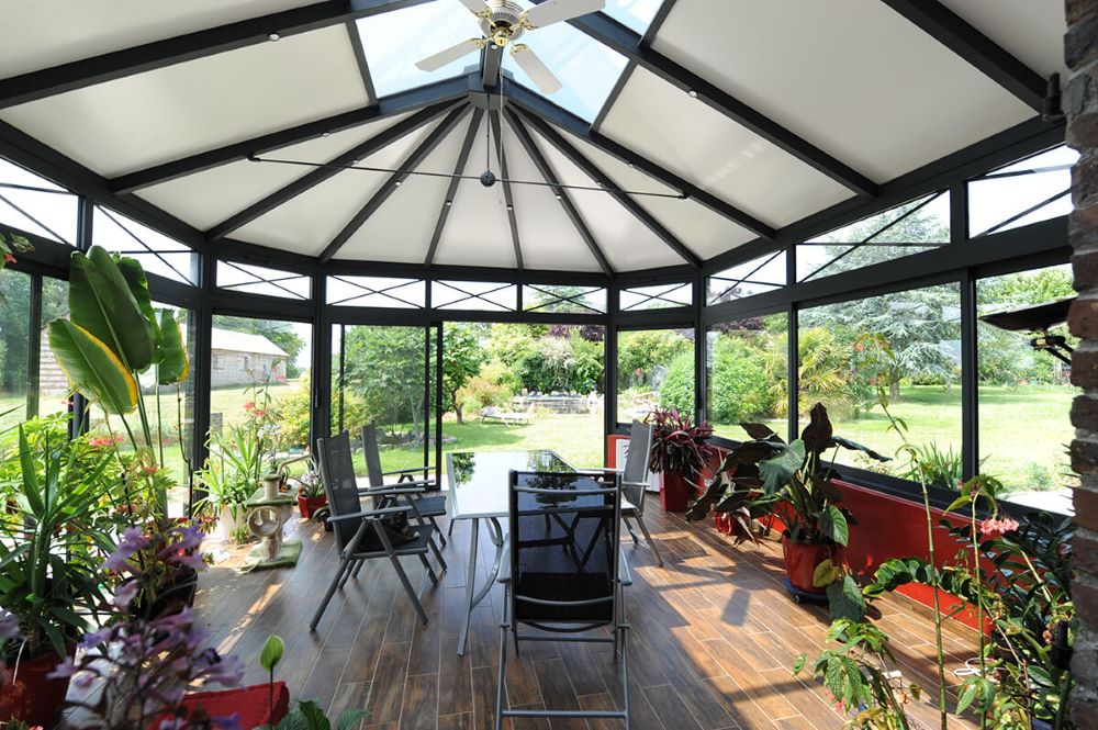 Jardin d'hiver lumineux avec structure aluminium et grandes baies vitrées accolé à une maison individuelle